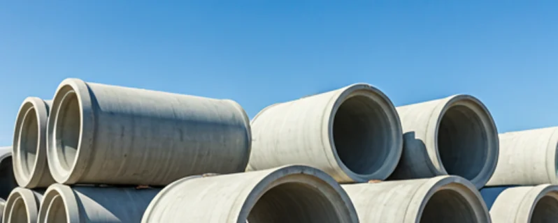 Large reinforced concrete drainage pipes stacked in an outdoor storage area